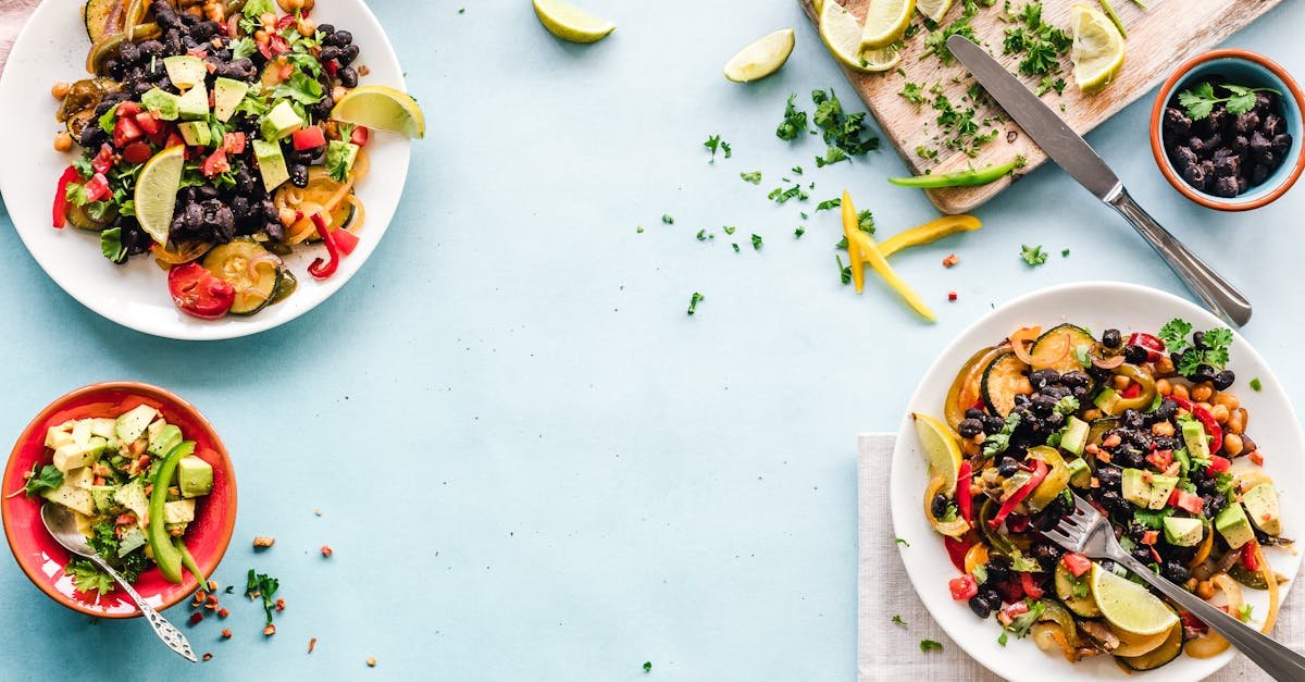Colorful Mexican salad with avocado, black beans, and lime on a light blue surface.